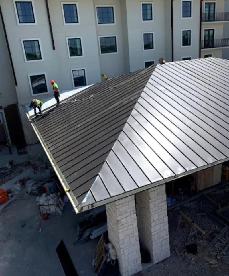 Crew installing standing seam metal roof panels on a commercial project in Creve Coeur